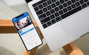 iPhone showing Facebook laying next to an Macbook