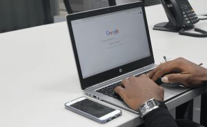 Google search on a HP laptop with an iPhone nearby on a white desktop